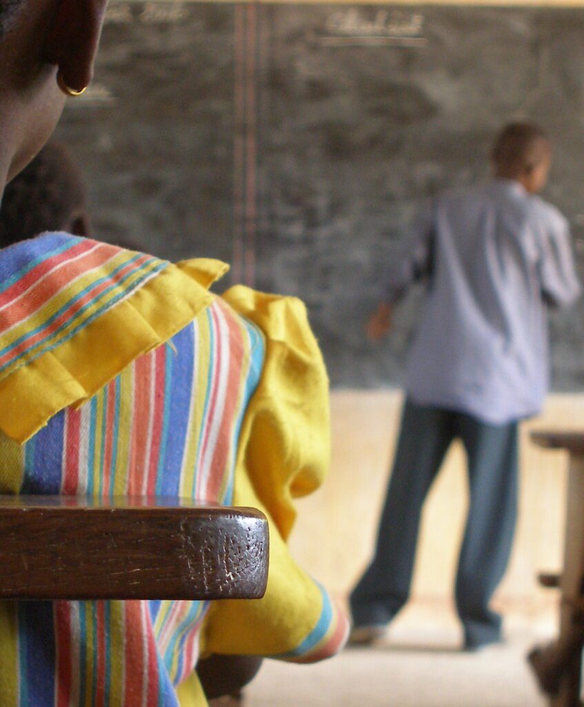 Girl in a school with teacher in background.